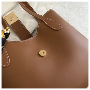 Detail of brown leather bucket bag with contrast stitching and magnetic clasp