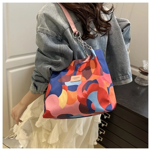Detail of colorful geometric print tote bag with pink leather strap and metal chain detail