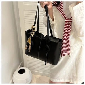 Close-up of black tote bag with white contrast stitching and elegant floral silk scarf