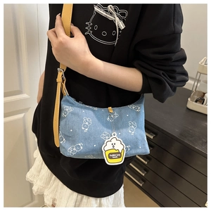 Detail of light blue denim shoulder bag with white bear print and yellow charm