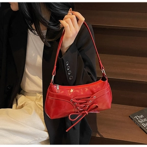 Close-up of a bright red PU leather bag with decorative lace-up bow and metal zipper detail