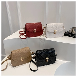 Close-up of four colorful woven saddle bags with teardrop gold buckles on white display steps