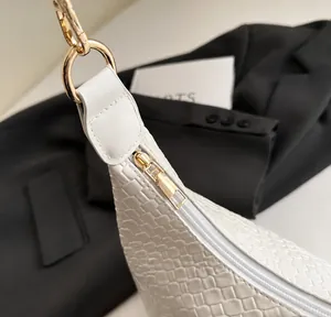 Vue détaillée de la fermeture éclair dorée et de la texture tissée du sac blanc en PU.