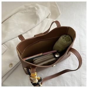 Top view of brown leather tote bag with silk scarf handle and spacious interior storage