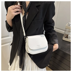 Close-up of white semi-circular saddle crossbody bag worn with a black blazer