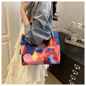Detail view of colorful nylon tote bag with leather handles and decorative metal chain