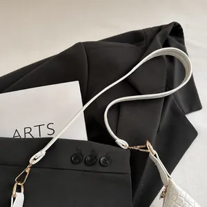 Détail d'une bandoulière de sac en PU tressé blanc avec un fermoir en métal doré