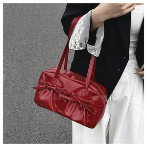 Glossy red shoulder bag with bow details and ruffles shown with a fashion outfit