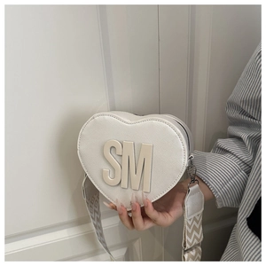 Close-up of white heart-shaped PU leather crossbody bag with SM logo and woven strap