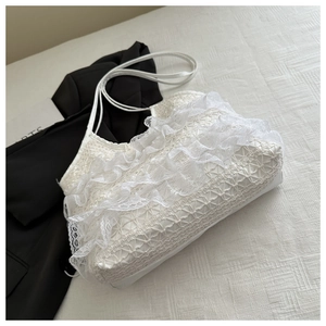 Detailed shot of white lace layered shoulder bag on fabric with black blazer background
