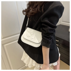 Gros plan du sac de selle en similicuir blanc avec texte embossé et bandoulière assortie