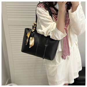 Detail of black tote bag featuring white contrast stitching and printed silk scarf on handle