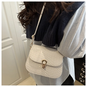 Close-up of white woven pattern crossbody bag with gold buckle on a shoulder model