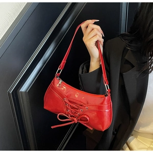 Detail of red faux leather shoulder bag with cross-lace and bow design accent
