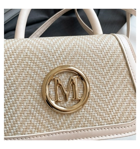 Detailed close-up of woven texture and gold M logo on the beige fashion box bag