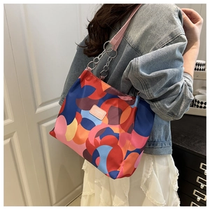 Detail of colorful geometric pattern shoulder bag with silver chain strap and pink logo
