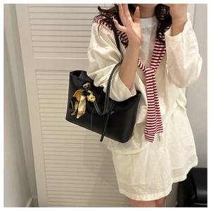 Detail of black leather tote bag with white contrast stitching and floral silk scarf charm