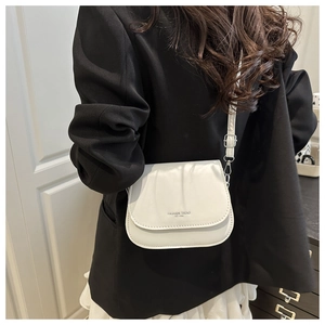 Detail of white saddle bag with FASHION TREND 1996 text on black blazer outfit