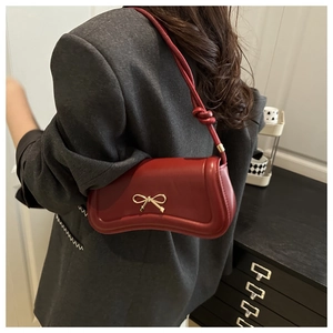 Close-up of burgundy bow-knot shoulder bag styled with a charcoal grey blazer