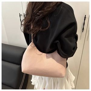 Détail du sac bandoulière rose clair en forme de croissant avec texture tissée sergée