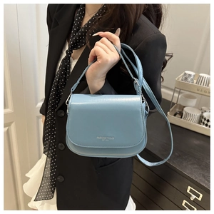 Sky blue leather handbag with silver lettering shown in a stylish fashion context