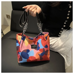 Detail of color-block tote bag featuring geometric patterns and metal chain handle