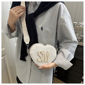 Detail of white heart-shaped bag with bold SM letter logo and patterned wide strap