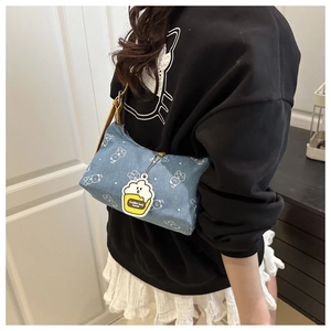 Detail of light blue denim shoulder bag with bear print and cupcake charm accessory