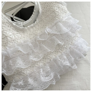 Close-up of layered white lace ruffles and mesh texture on a stylish tote bag