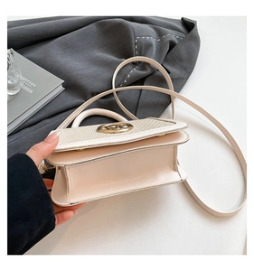 Detail of a chic cream leather crossbody bag with textured woven flap and gold buckle