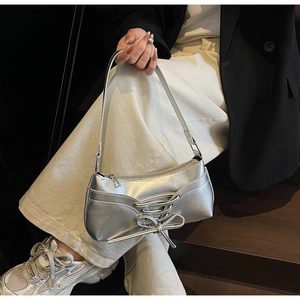 Detail of silver PU leather underarm bag with bow decoration and stylish cross straps