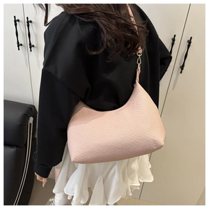 Pink shoulder bag detail showing adjustable strap and textured surface on model