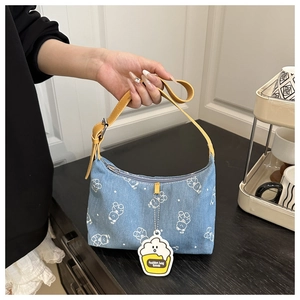 Close-up of light blue denim shoulder bag with bear prints and yellow leather handle