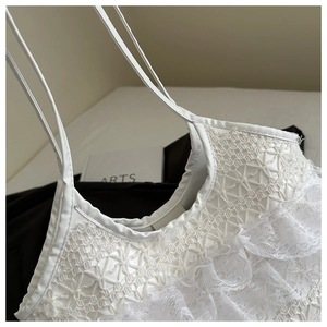 Close-up of white camisole with geometric mesh embroidery and tiered lace details
