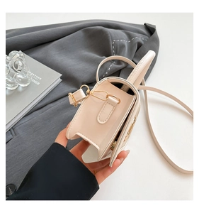 Detail of cream-colored box bag showing textured leather and golden hardware accents