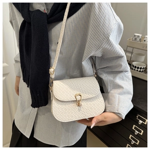 Detail of white crocodile texture leather bag with elegant golden horseshoe buckle strap