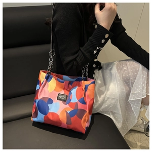 Close-up of vibrant geometric circle print tote bag with metal chain strap on model