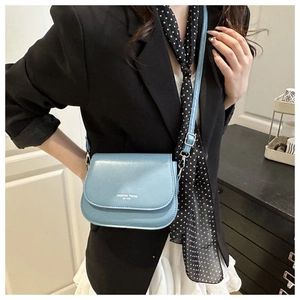 Sacoche bleue avec lettrage blanc portée avec une tenue urbaine élégante et chic