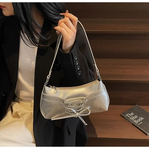 Detail of silver metallic pleated underarm bag with bow tie straps and ballet style design