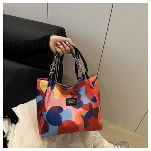 Detail of colorful geometric print tote bag featuring black handle with silver chain