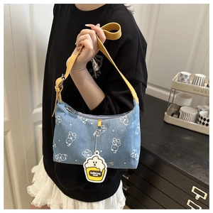 Detail of blue denim shoulder bag featuring white bear prints and a yellow leather strap