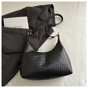 Detailed view of a black woven textured PU leather underarm bag on a stylish background