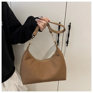 Gros plan sur la texture tissée marron du grand sac porté épaule avec fermeture dorée