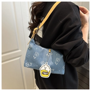 Detail of blue denim shoulder bag featuring white bear prints and yellow fashion tag