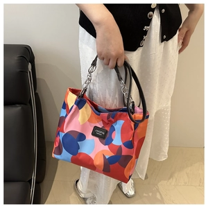 Detail of multi-color geometric patchwork tote bag with metal chain and brand label