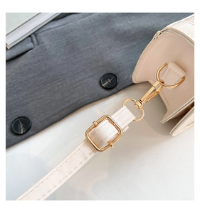 Close-up of premium gold hardware hooks and adjustable buckle on cream crossbody bag