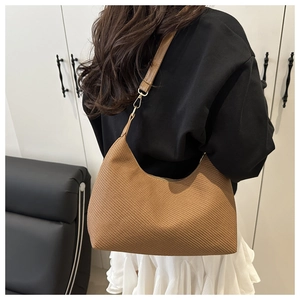 Détail de la texture tressée et des ferrures dorées d'un sac à bandoulière hobo marron