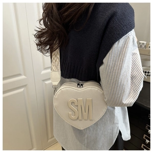 White heart-shaped crossbody bag with SM logo and woven geometric strap detail