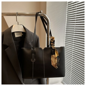 Detail of black tote bag featuring white contrast stitching and a printed silk scarf handle