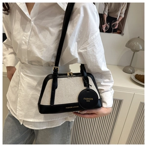 Detail of minimalist shell bag in canvas and black leather worn as an elegant shoulder bag